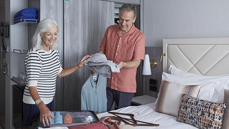 A couple unpacking their suitcase in their cabin on Spirit of Adventure